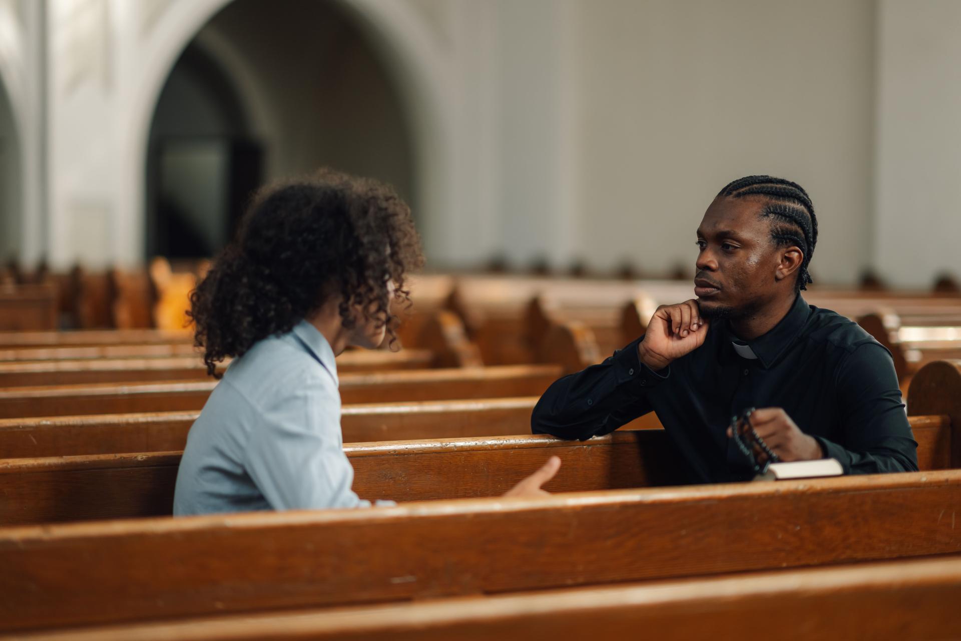 Priest listening to young man talking about problems in church