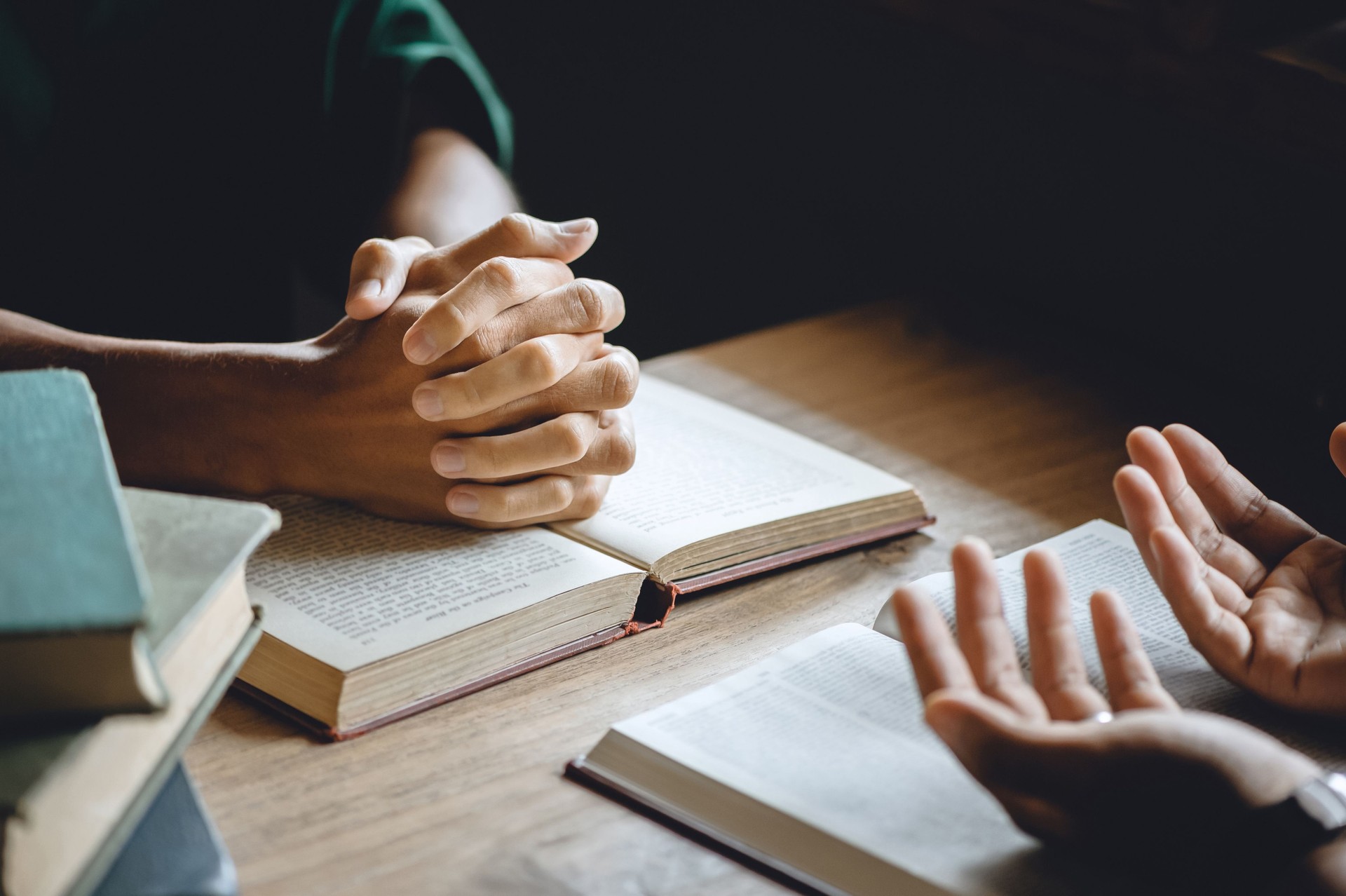 Christian group of people holding hands praying worship to believe and Bible on a wooden table for devotional or prayer meeting concept."n
