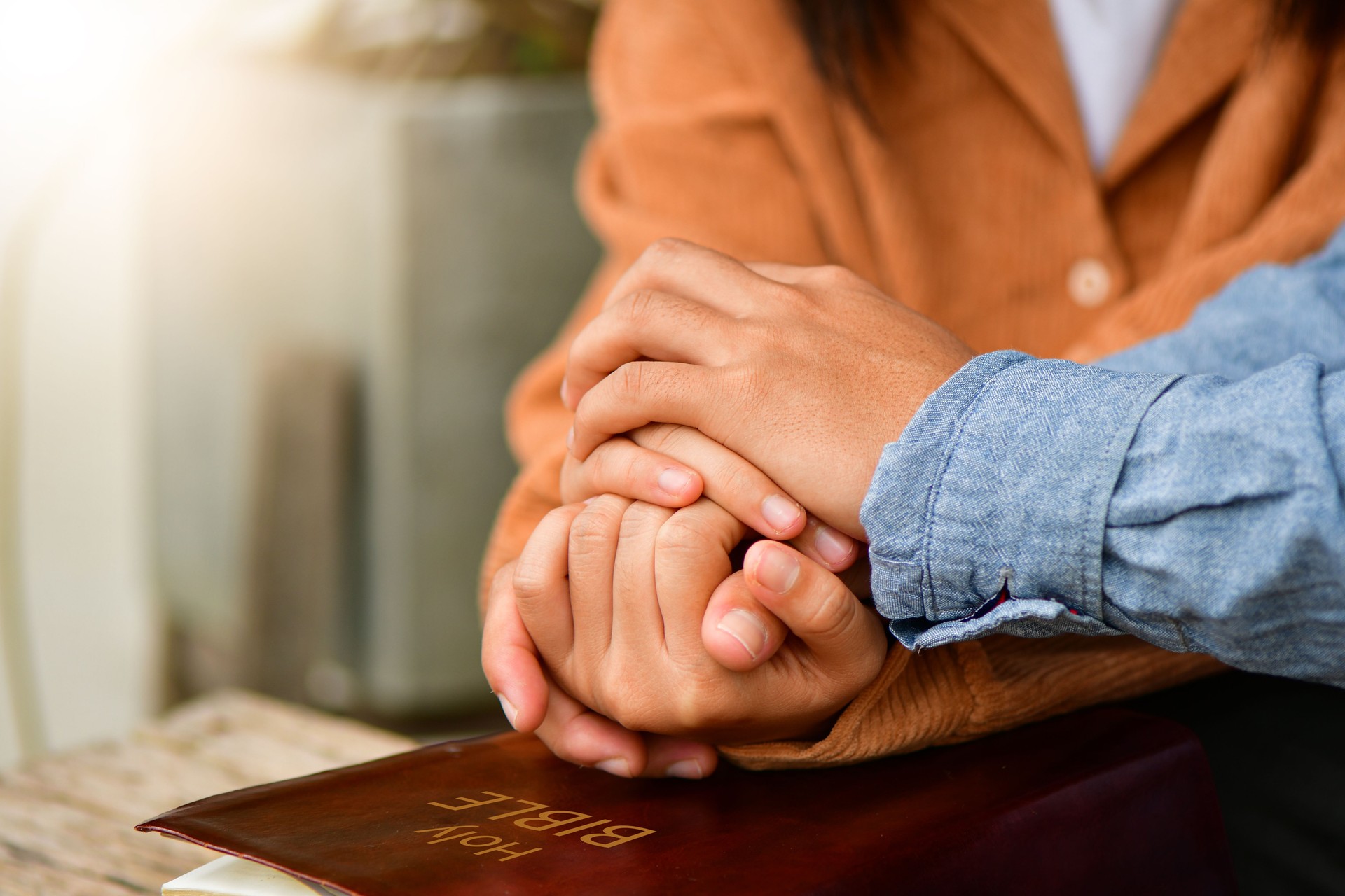 Couple are pray together, hands in prayer together over an open Holy Bible. Christian life crisis prayer to god.
